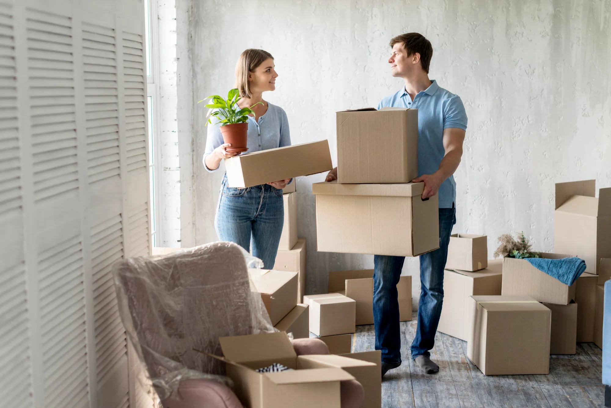 A couple carrying boxes into their new apartment